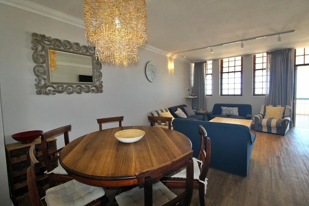 Open-plan dining and lounge area with round wooden table and blue upholstered seating