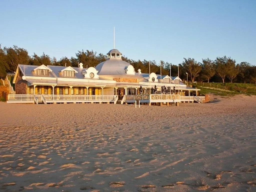 Distinctive yellow and white beach pavilion with dome on sandy shore