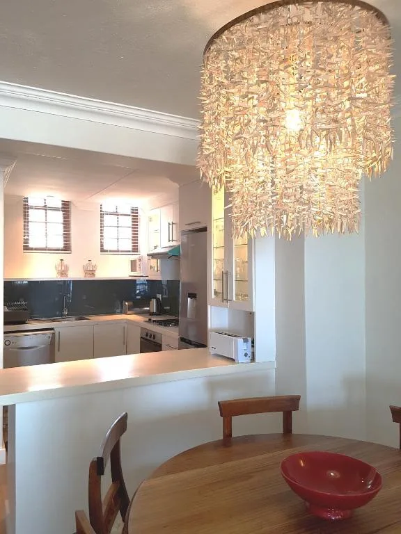 Modern kitchen with white cabinetry, black backsplash, and decorative chandelier overhead