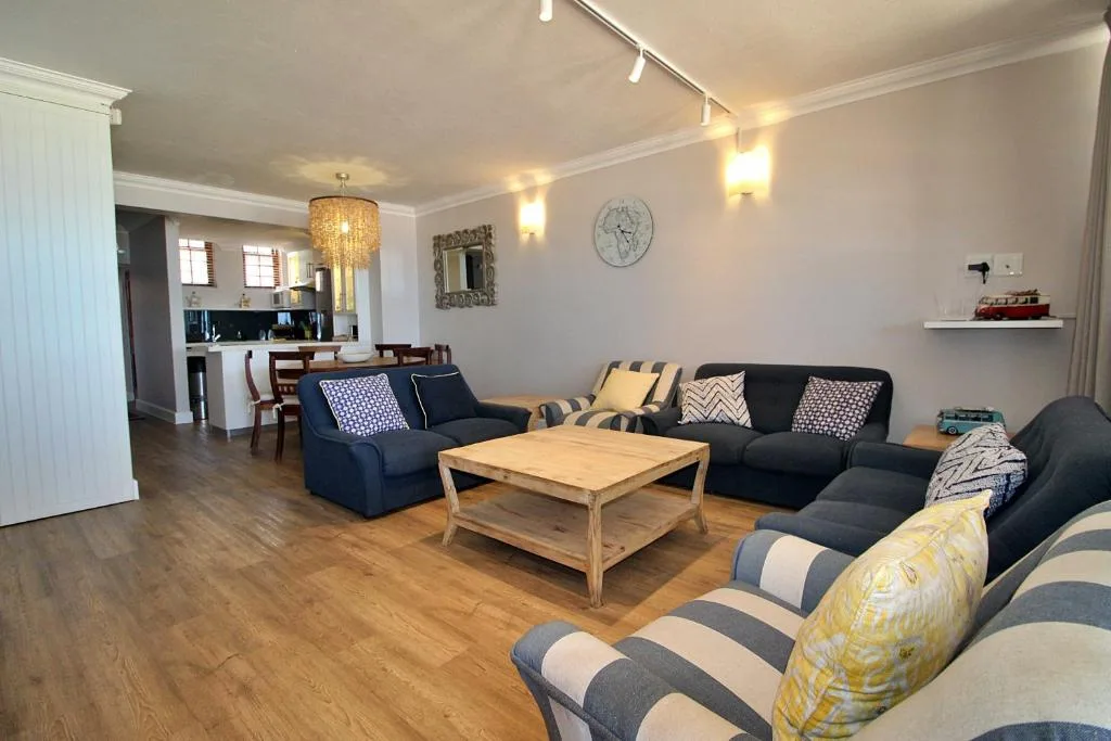 Spacious living room with dark sofas, wooden coffee table, and modern lighting.