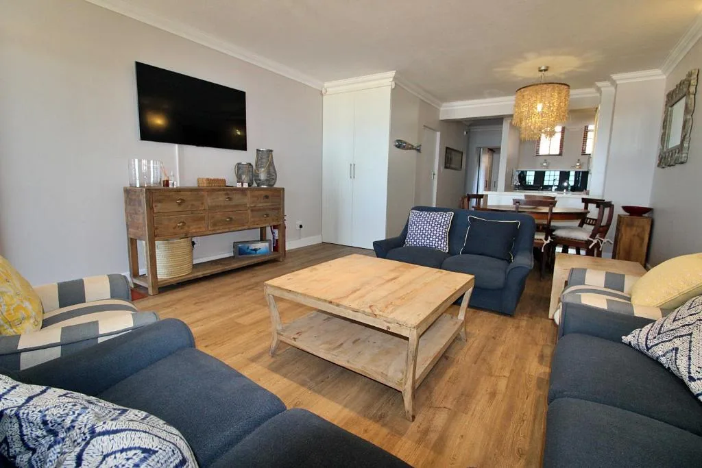 Open-plan lounge with navy sofas, wooden coffee table, and wall-mounted TV