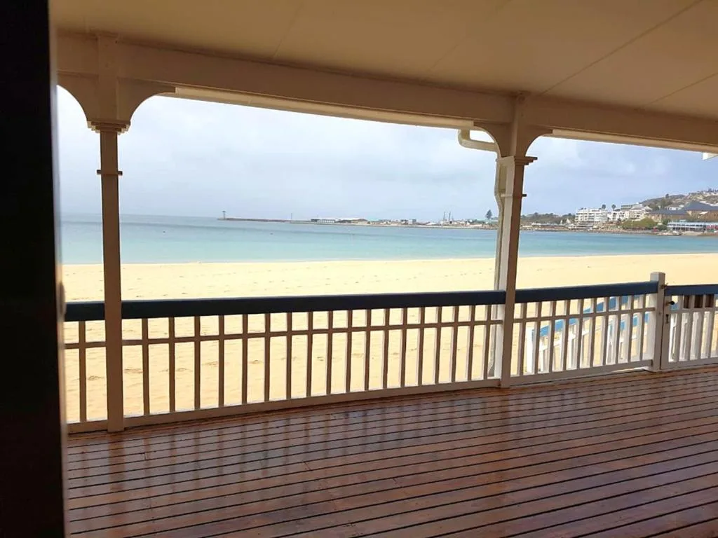 Panoramic beach and ocean view from covered wooden deck overlooking sandy shore