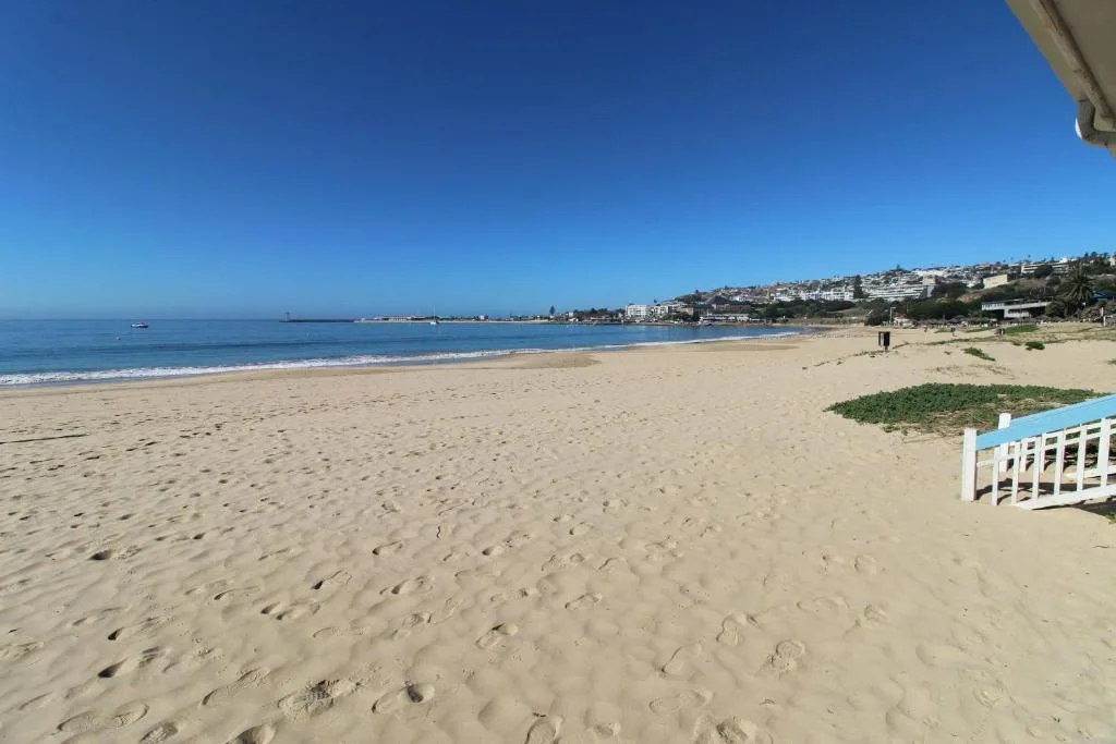 Golden sandy beach with blue ocean, coastal town, and clear sky backdrop