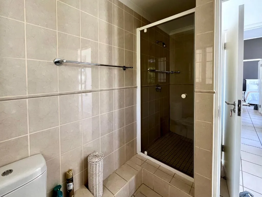 Modern shower enclosure with glass door and beige tile walls