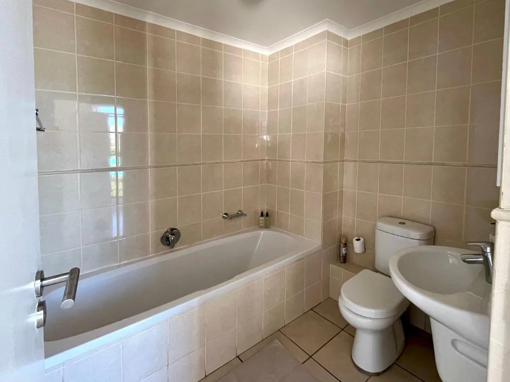 Clean bathroom with bathtub, toilet, sink, and beige tile walls