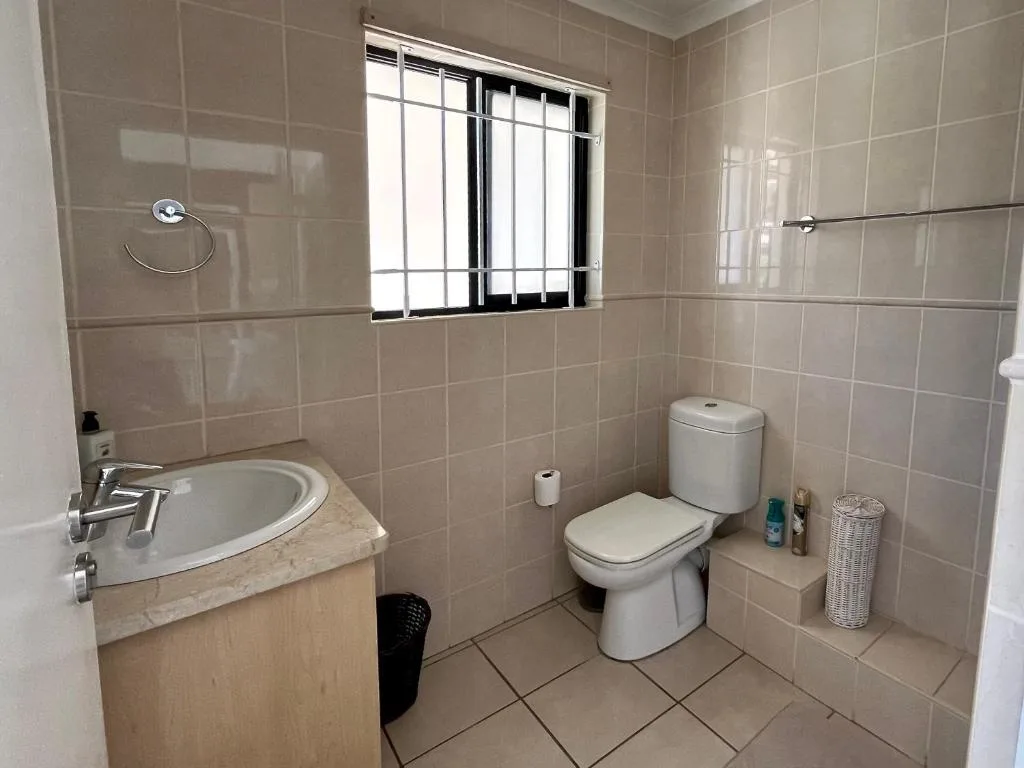 Clean bathroom with vanity sink, toilet, and tiled walls and floor