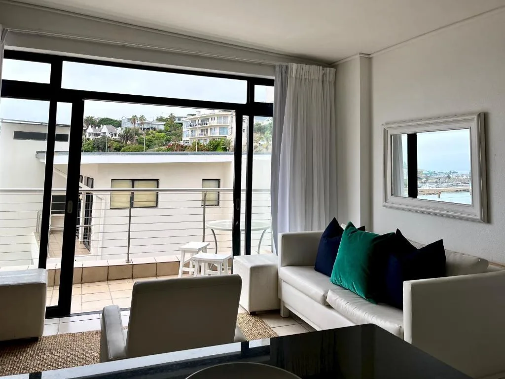 Modern lounge with cream sofa, colorful pillows, and ocean views through large windows
