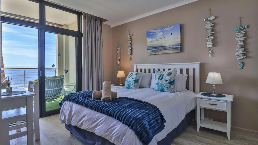 Spacious bedroom with ocean view through glass doors and coastal decor