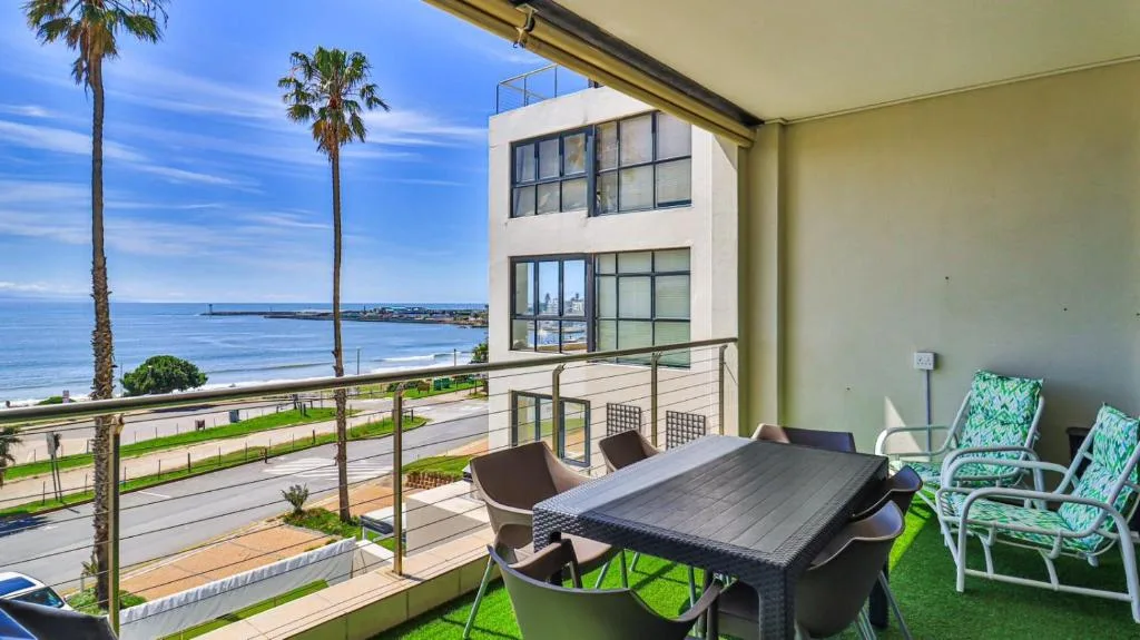 Seaside deck with dining table, lounge chairs, ocean and palm trees