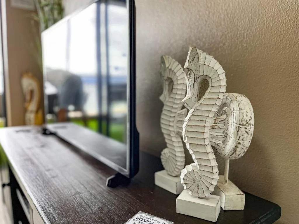 White carved seahorse sculpture displayed on dark windowsill with ocean view