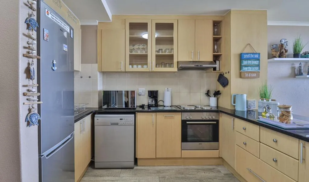 Modern kitchen with wooden cabinets, stainless steel appliances, and black countertops
