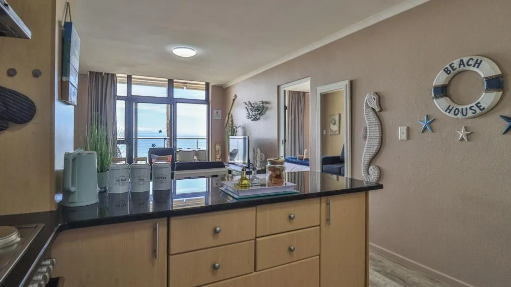 Modern kitchen with black countertop overlooking ocean view through large windows