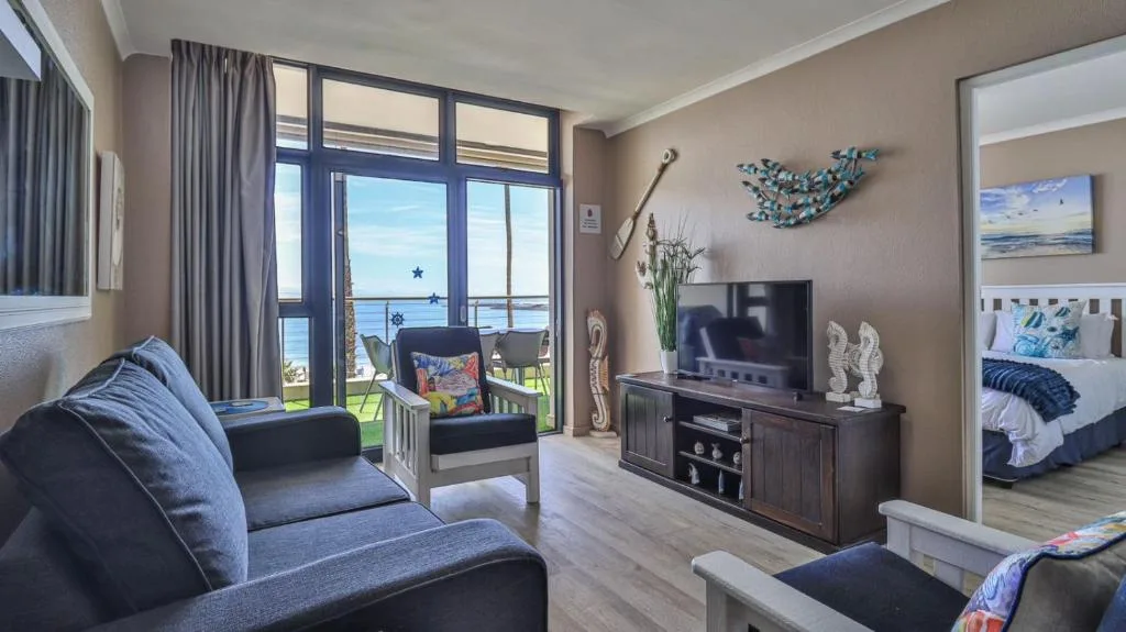 Modern lounge with blue sofa, TV, ocean view through glass doors