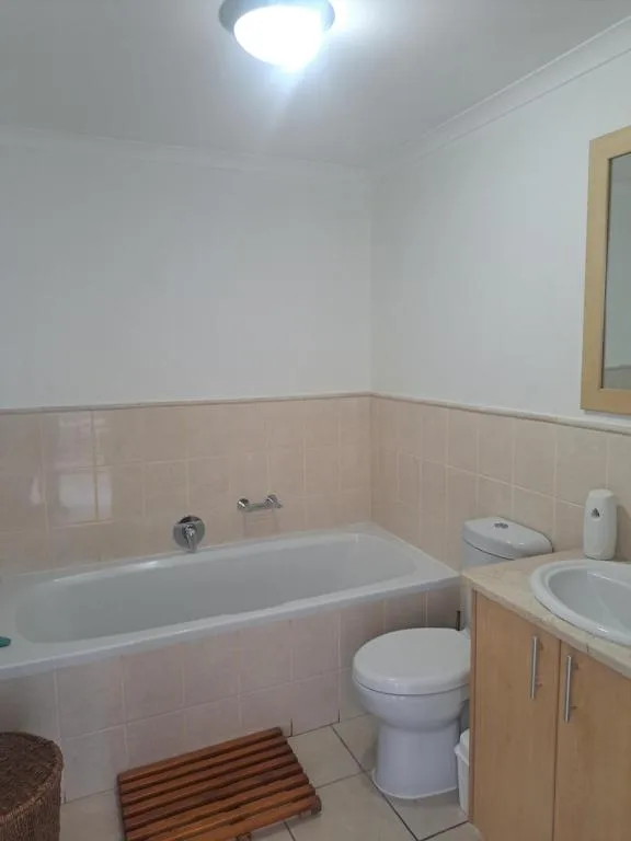 Bathroom with bathtub, toilet, vanity, and tiled walls