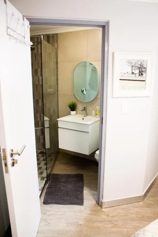 Modern bathroom with round mirror, white vanity, and walk-in shower