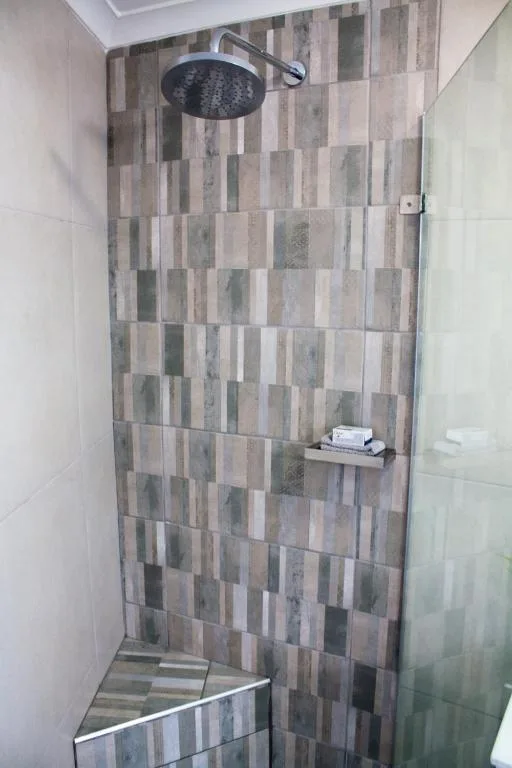 Modern walk-in shower with geometric tile pattern and rainfall showerhead