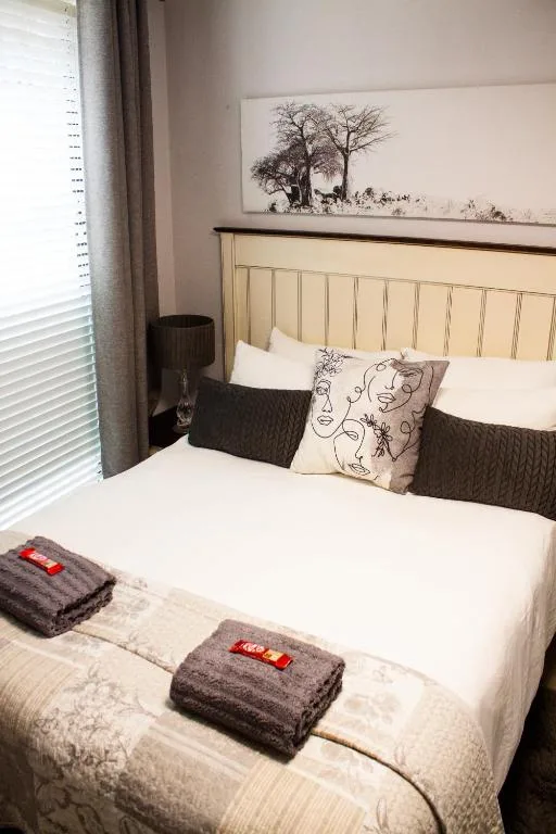 Comfortable bedroom with cream headboard, decorative pillows, and folded towels
