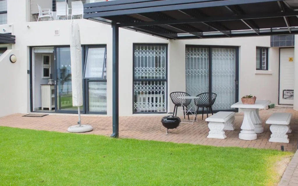 Patio with seating furniture, umbrellas, and manicured lawn garden