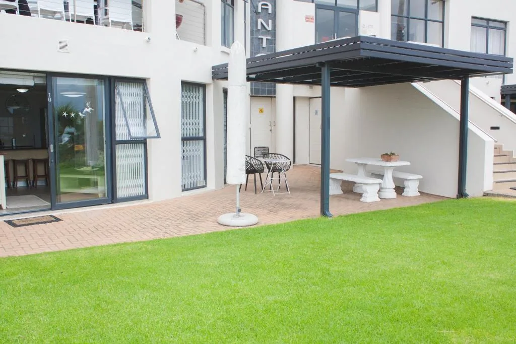Modern patio with pergola, seating, and manicured lawn area