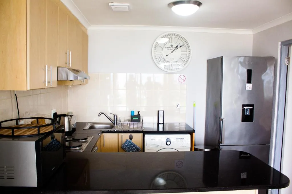 Modern kitchen with wooden cabinetry, stainless steel appliances, and black countertops