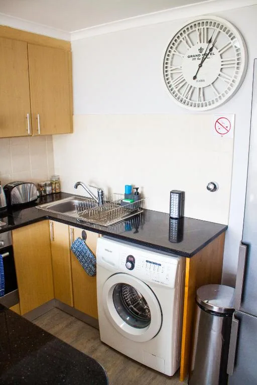Kitchen with wooden cabinets, washing machine, sink, and wall clock
