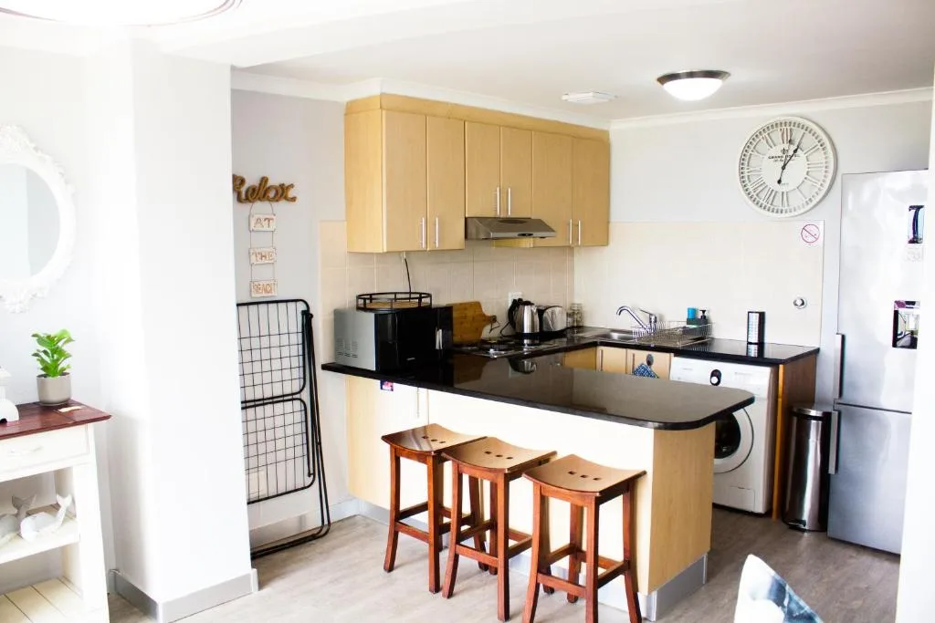 Modern kitchen with wooden cabinetry, black countertops, and bar seating