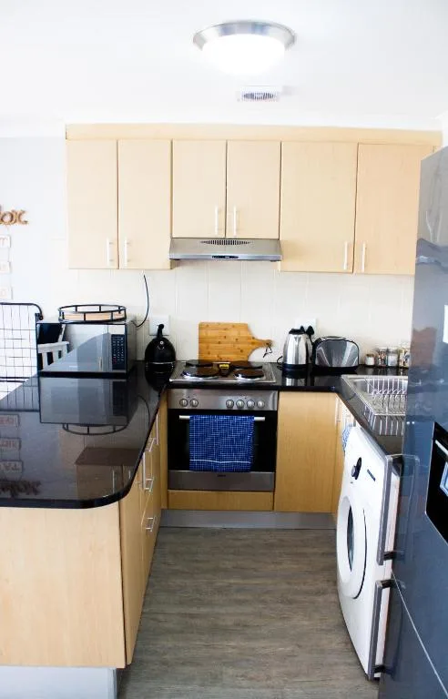 Compact kitchen with light wood cabinets, stove, and washing machine