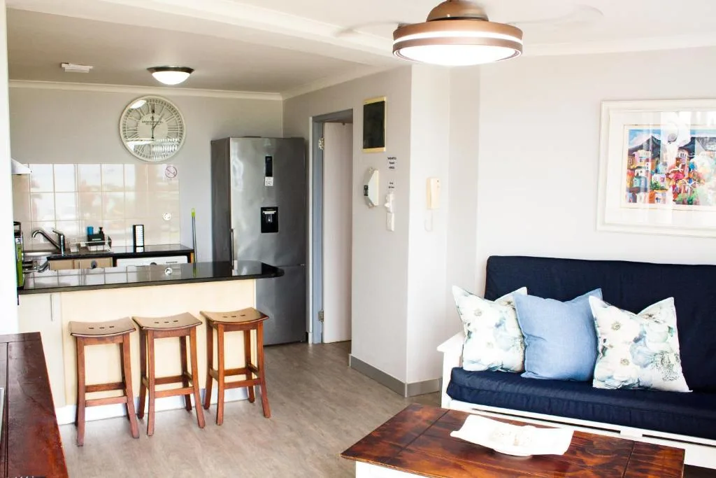 Open-plan lounge with navy sofa, wooden coffee table, and kitchen visible behind