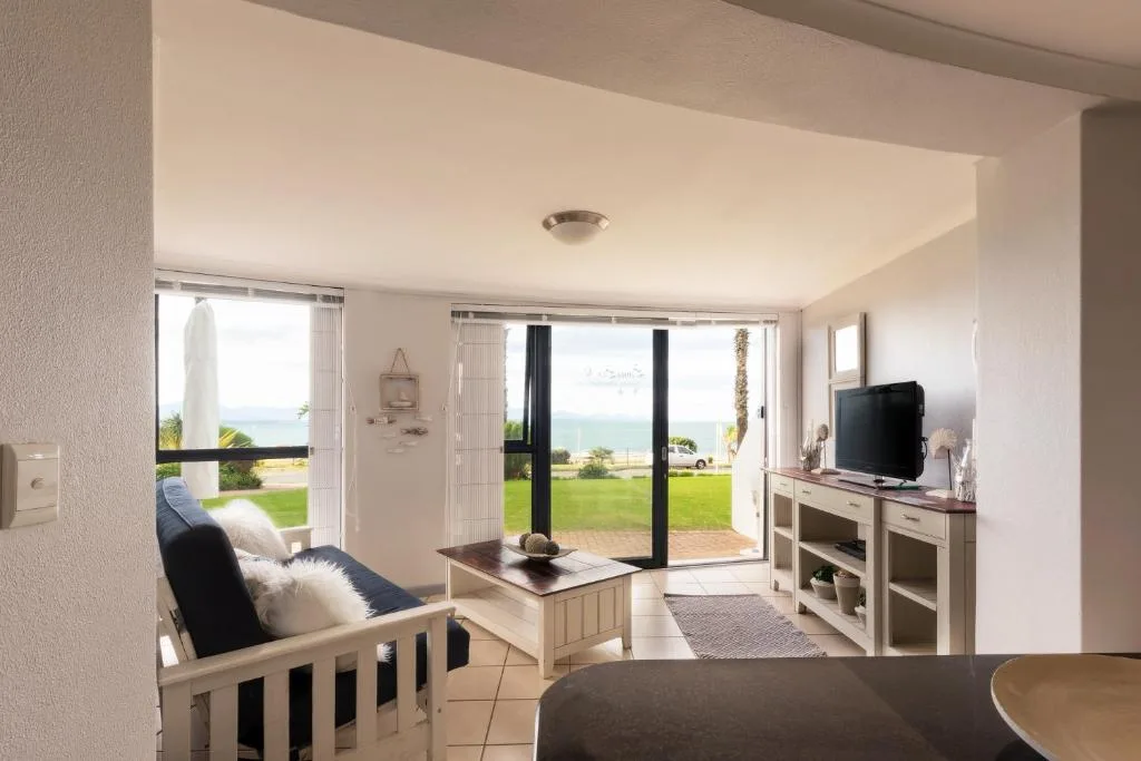 Bright lounge with ocean view through glass doors and TV entertainment unit