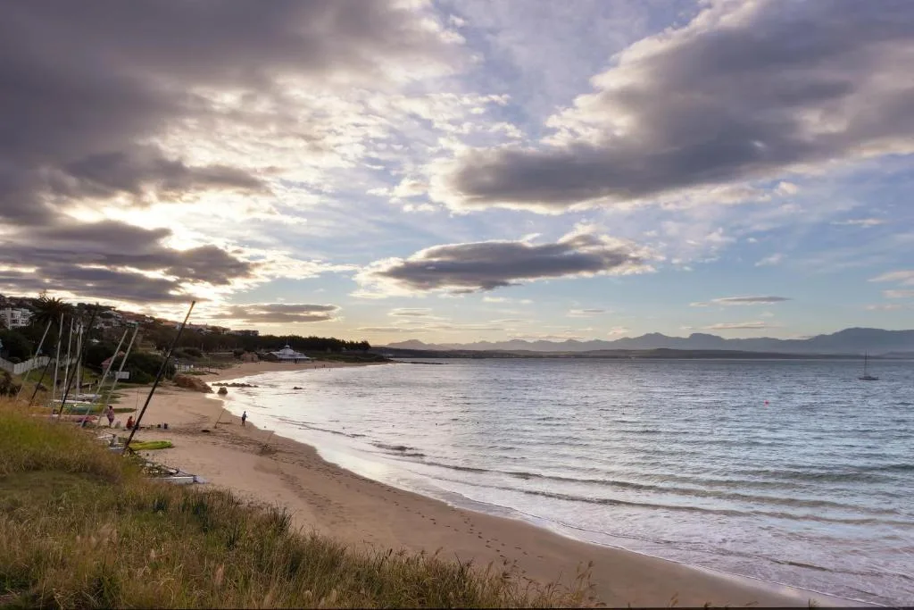 Scenic beach and ocean view with mountains in distance and dramatic clouds