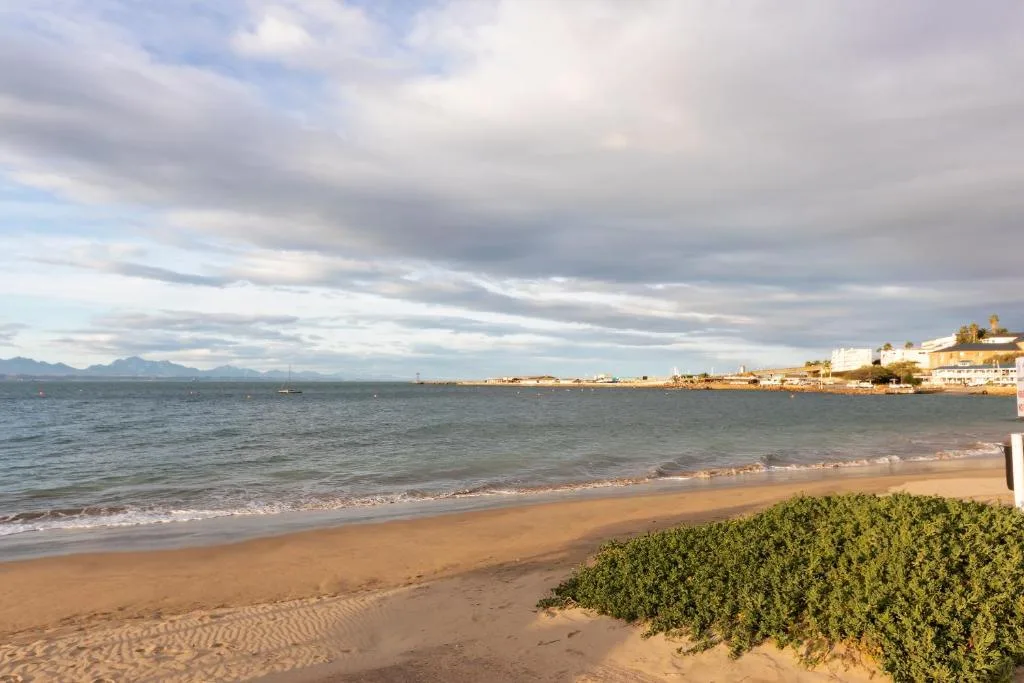 Scenic beach view with mountains and coastal town buildings in distance
