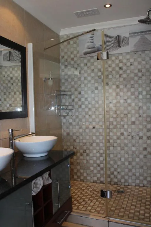 Modern bathroom with vessel sink, walk-in shower, and mosaic tile walls