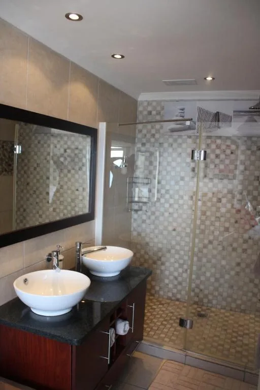 Modern bathroom with dual vessel sinks, large mirror, and glass shower enclosure