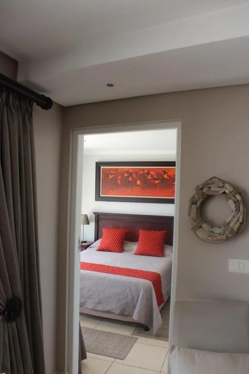Bright bedroom with red accent pillows and modern artwork above bed