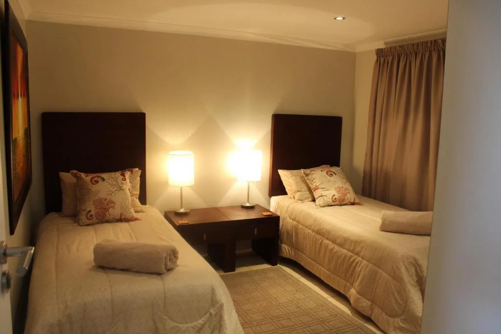 Twin bedroom with dark headboards, soft lighting, and neutral décor