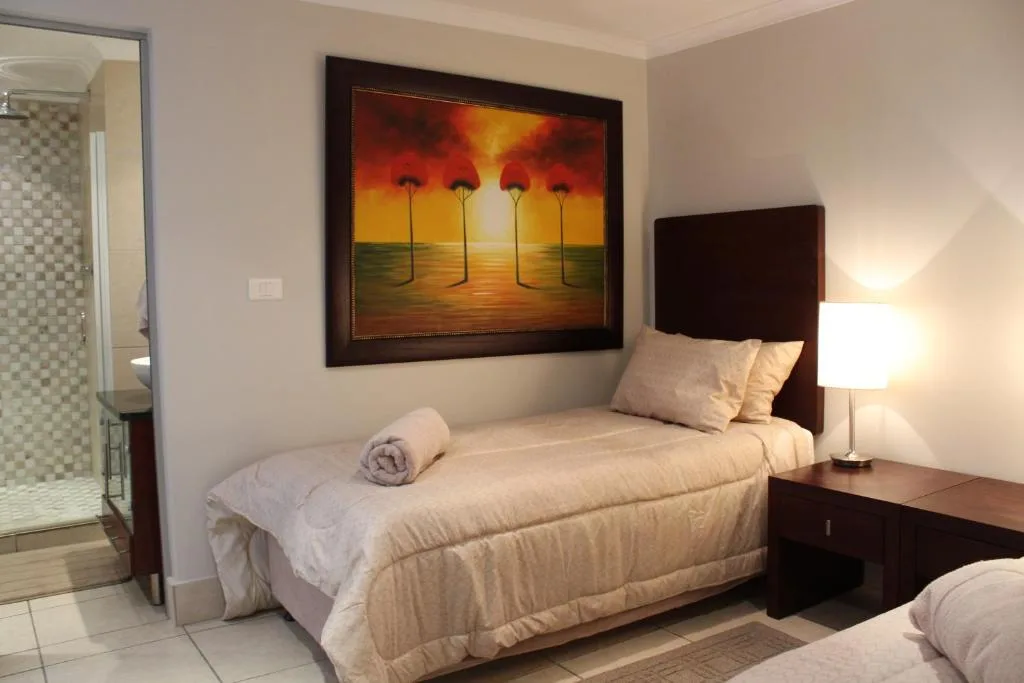 Bedroom with single bed, dark headboard, sunset artwork, and en-suite bathroom