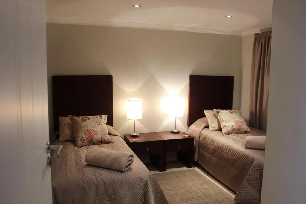 Twin bedroom with dark headboards, patterned pillows, and bedside lamps