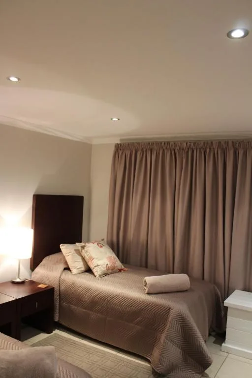 Spacious bedroom with double bed, brown headboard, and floor-to-ceiling curtains