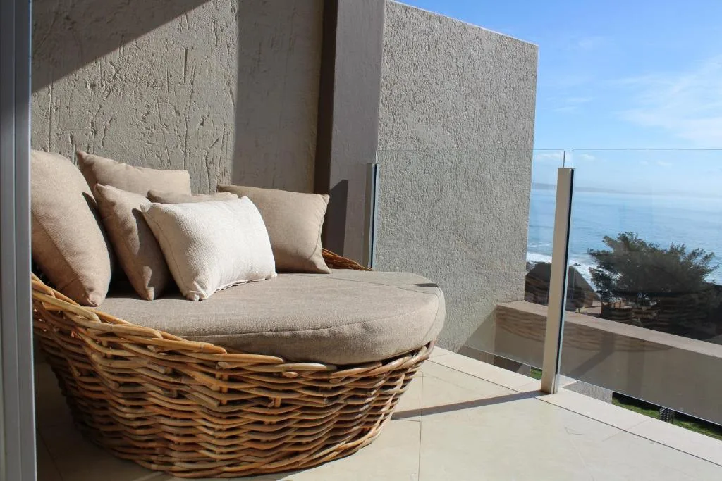 Wicker lounge chair with cushions on oceanview deck with glass railings