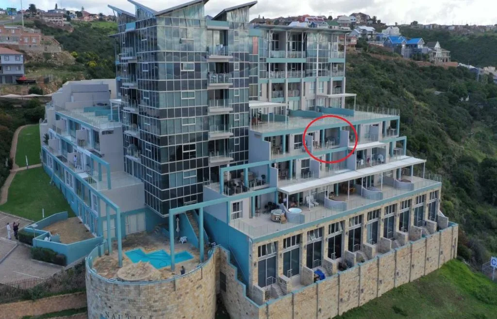 Modern multi-story seafront apartment building with glass and stone facade overlooking Mossel Bay