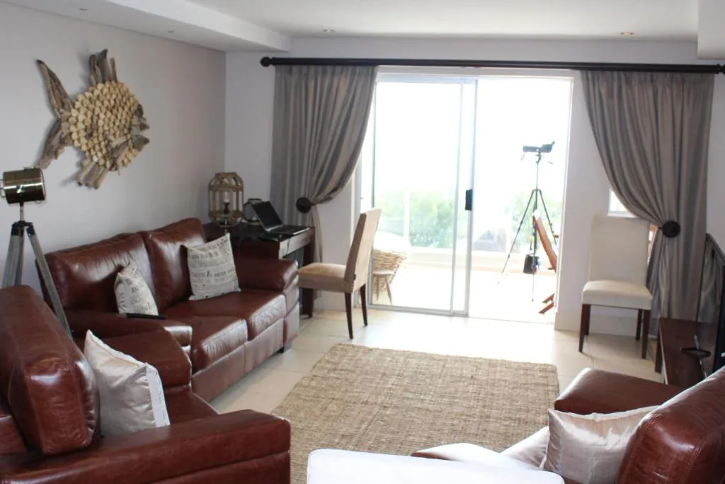 Spacious living room with burgundy leather sofas and ocean view doors