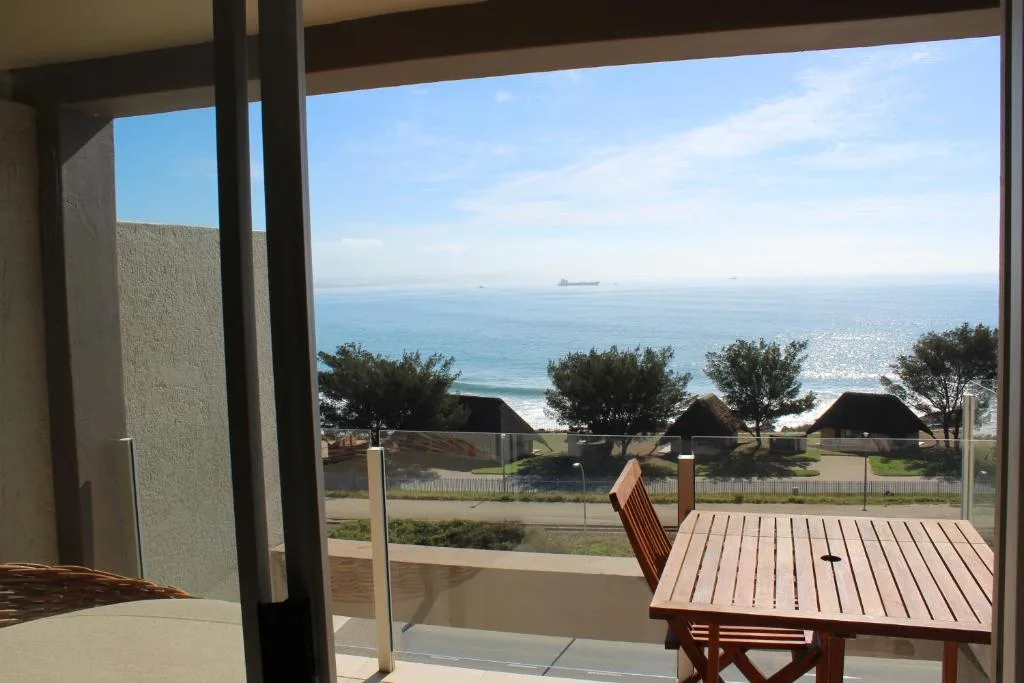 Ocean and coastline vista from beachfront property with garden furniture