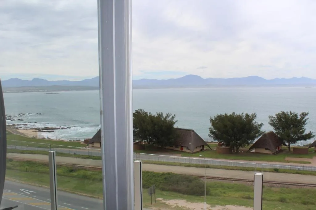 Ocean and mountain vista from large window with coastal buildings below