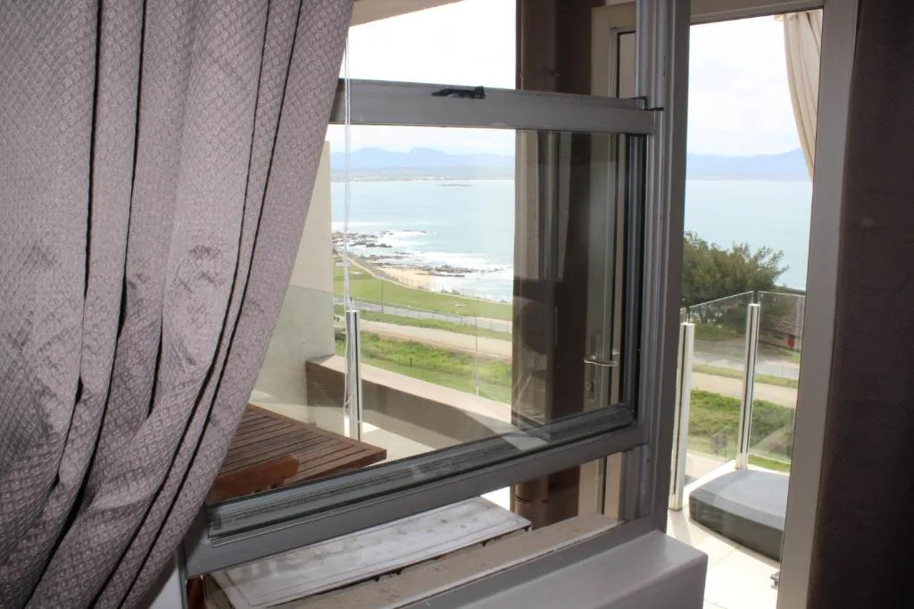Coastal view of beach and ocean through open glass doors from bedroom