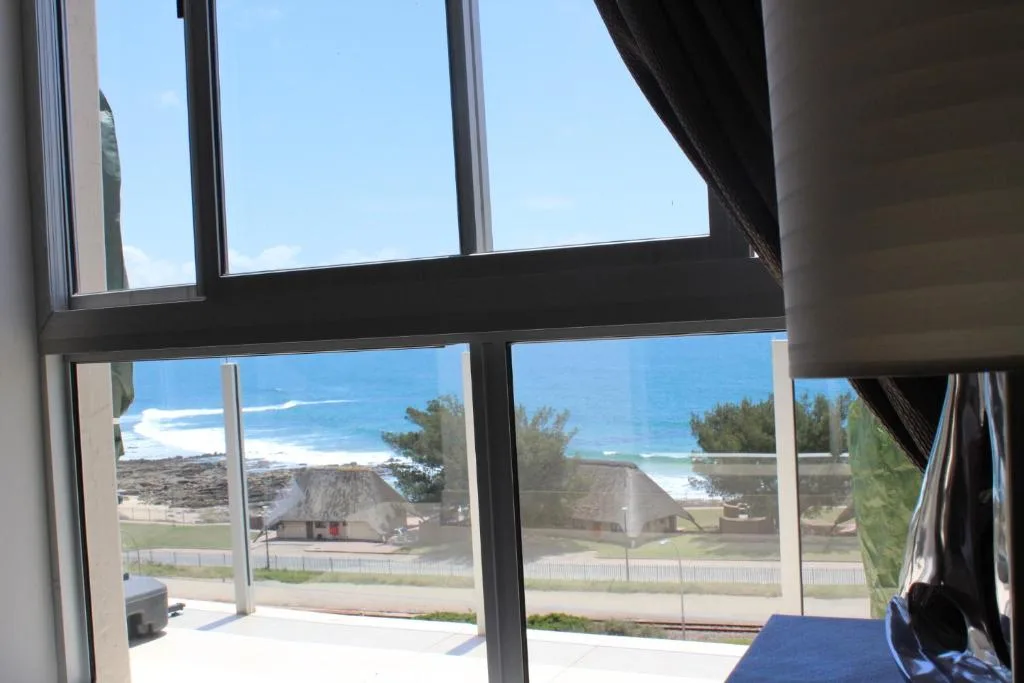 Ocean and coastal landscape visible through modern interior windows and glass doors