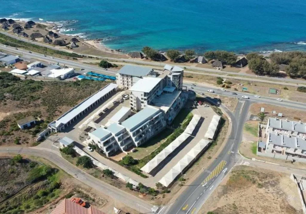 Aerial view of oceanfront apartment complex with turquoise sea beyond