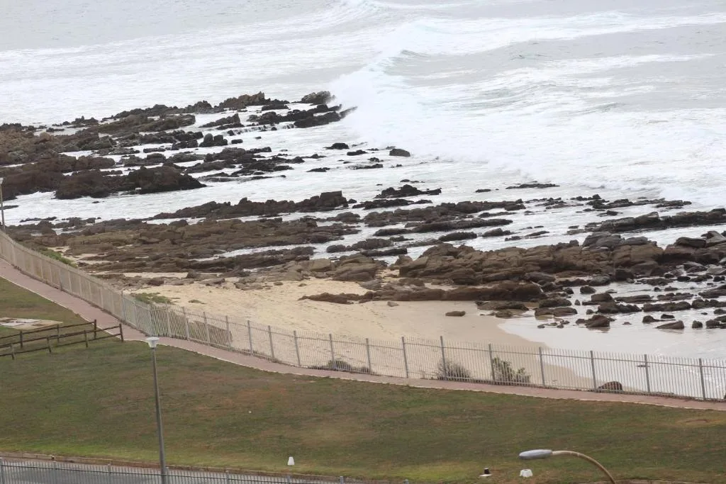 Rocky coastline with sandy beach and crashing white waves below