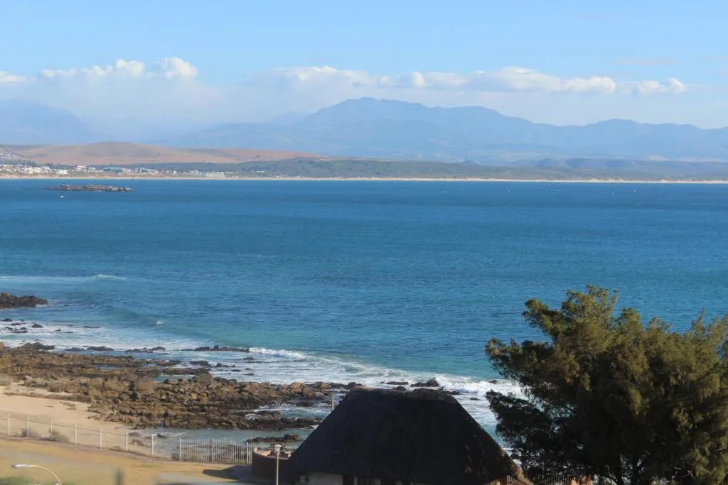 Panoramic ocean view with mountains, beach, and coastal town in distance