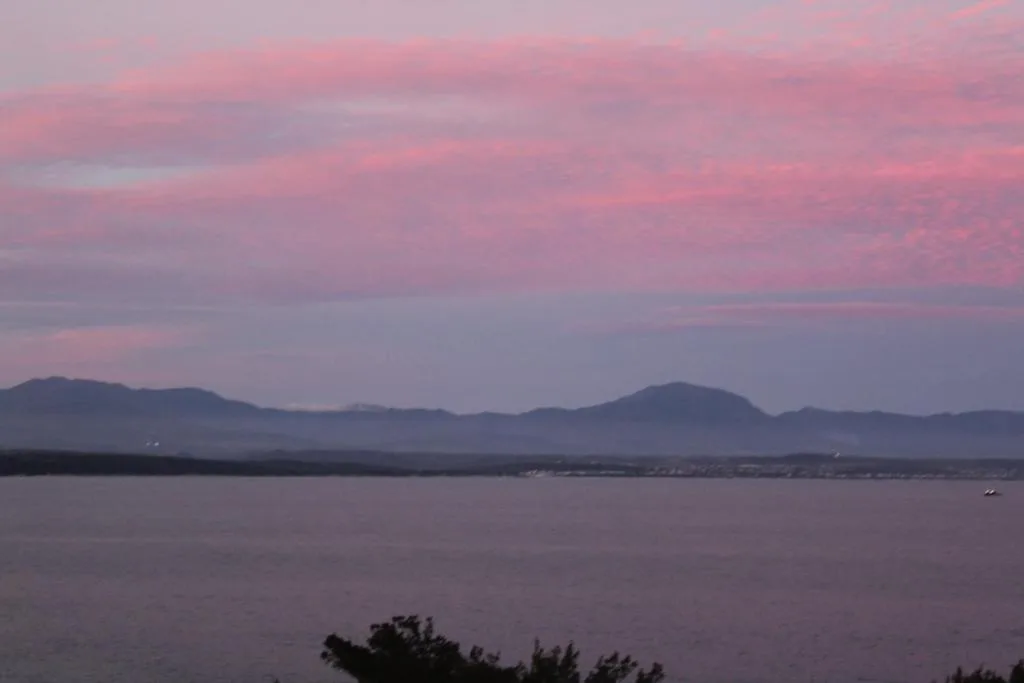Sunset over calm lagoon with distant mountains and coastal landscape