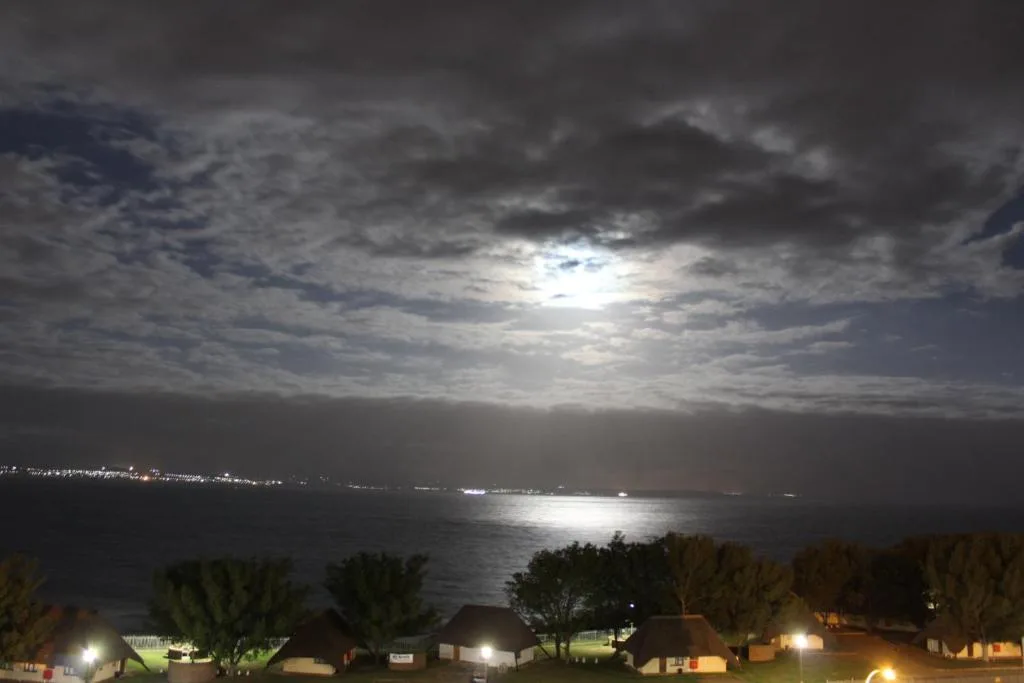 Moonlit ocean view at dusk with coastal town lights below